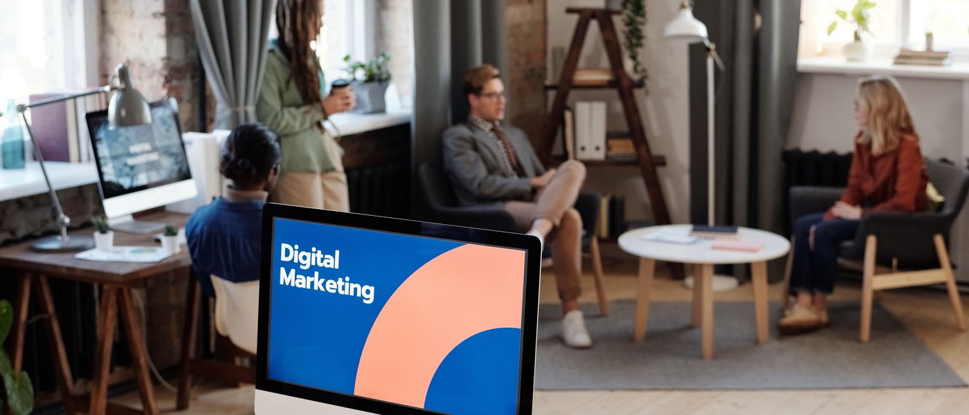 A digital marketing presentation on a screen in a busy studio office